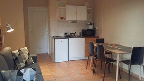 A compact living space with a kitchenette, a dining area, and a sofa.