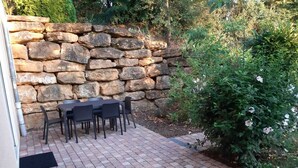 A patio with a stone wall, a table, and chairs.
