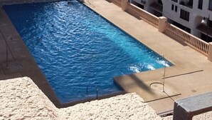 A swimming pool with a view of white buildings and a clear sky. - Luxury penthouse overlooking the golf course of Almerimar. (Almerimar)