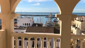 A balcony with a view of a marina and buildings. - Luxury penthouse overlooking the golf course of Almerimar. (Almerimar)