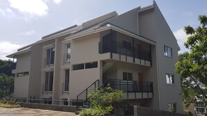 A modern multi-story building with balconies, a staircase, and a concrete pathway. - Residence Bel Eau (Mahé Island)