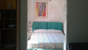 Une pièce comprenant un lit, une armoire en bois et un tableau coloré accroché au mur.