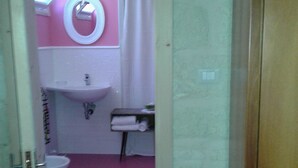 Une salle de bain avec un mur rose, un lavabo blanc et un miroir.