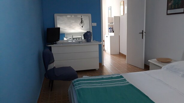 Une chambre à coucher comprenant un lit, un bureau avec une chaise, une commode et un miroir.