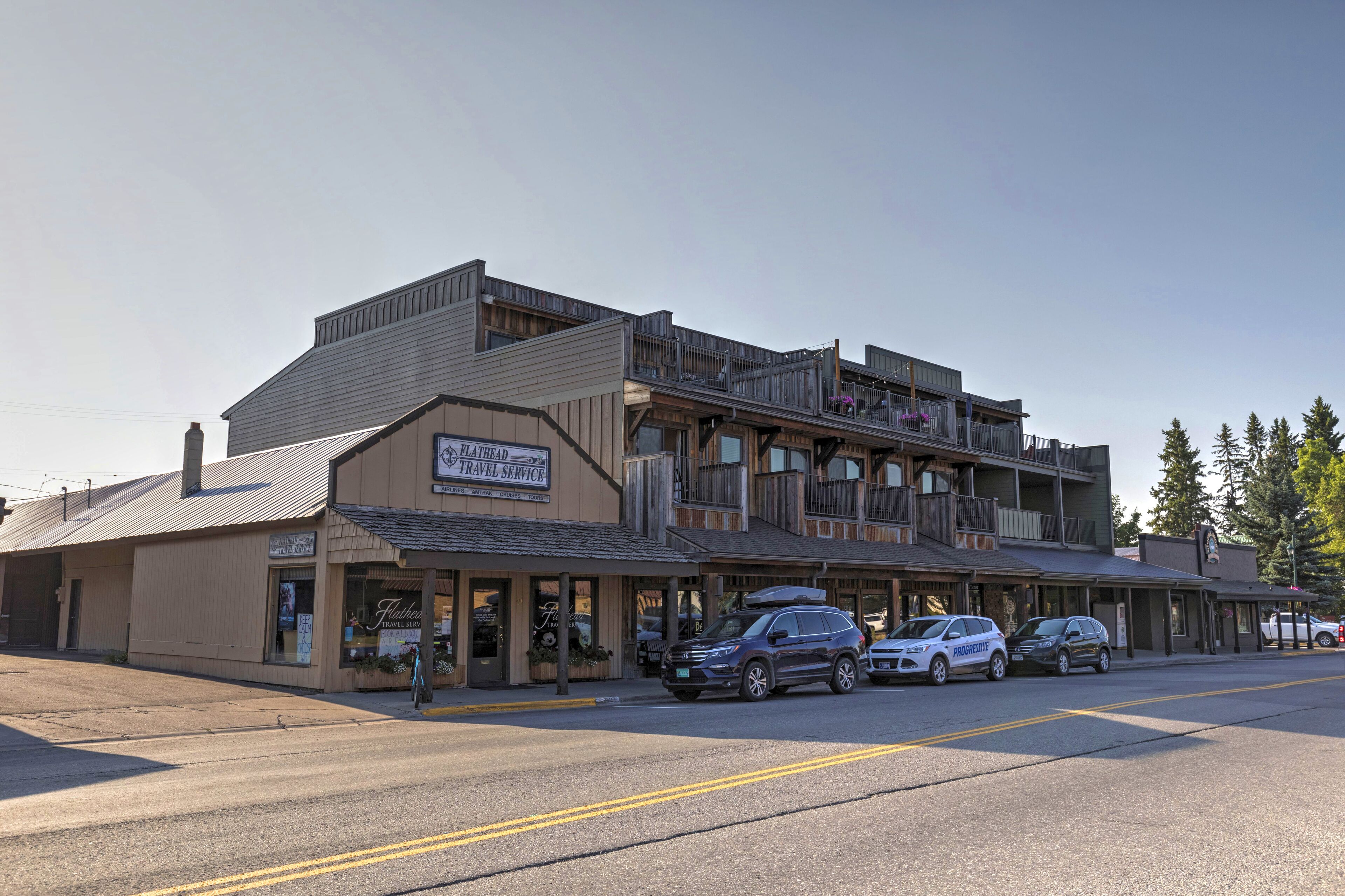 A building with a flat roof, a sign for Flathead Travel Service, and a balcony with railings.