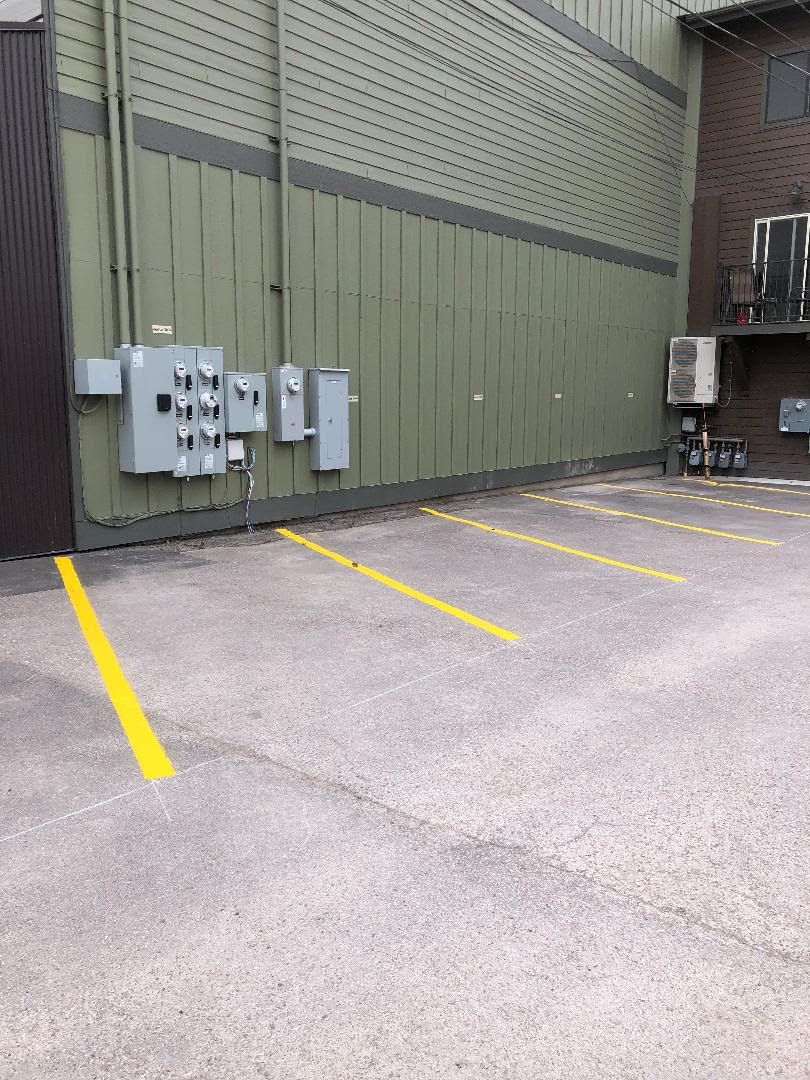 Een parkeerplaats met aangegeven parkeerplaatsen en elektrische dozen aan de muur.