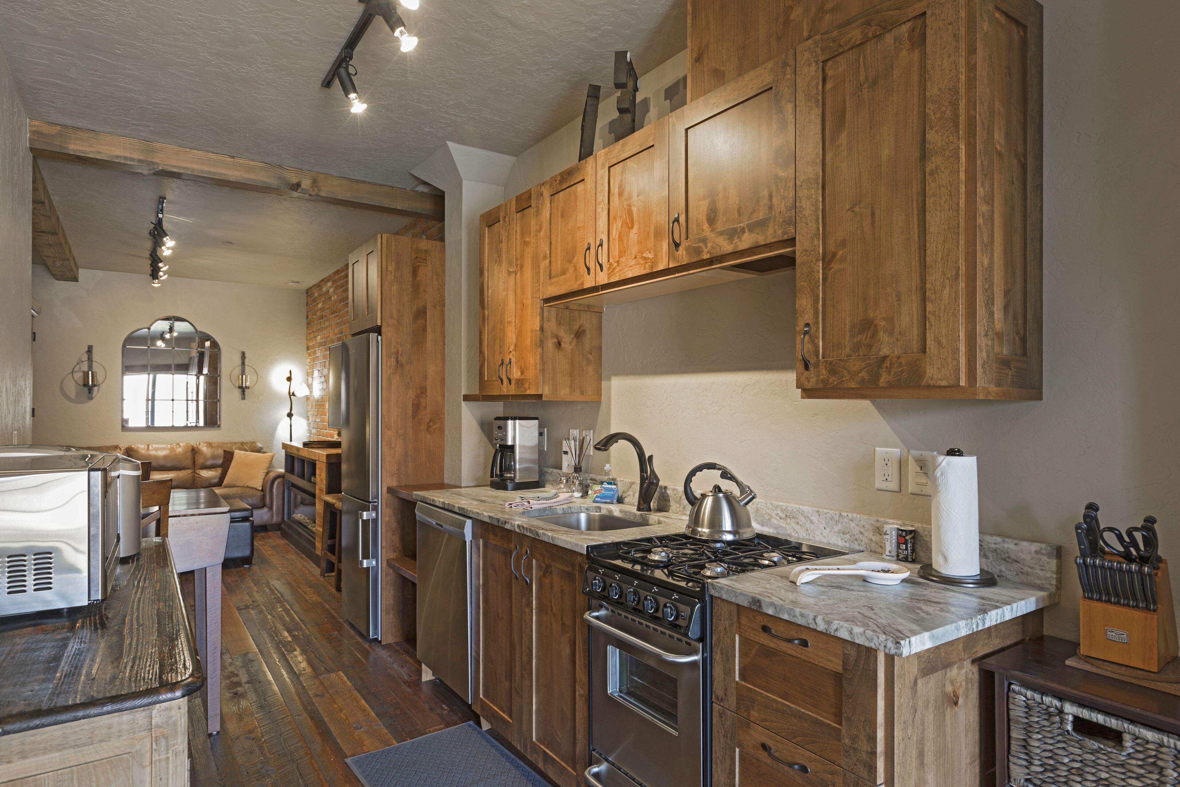 A kitchen with wooden cabinets, stainless steel appliances, and a marble countertop.