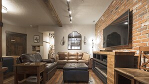 A cozy living room with a leather sofa, a wooden coffee table, and a fireplace.