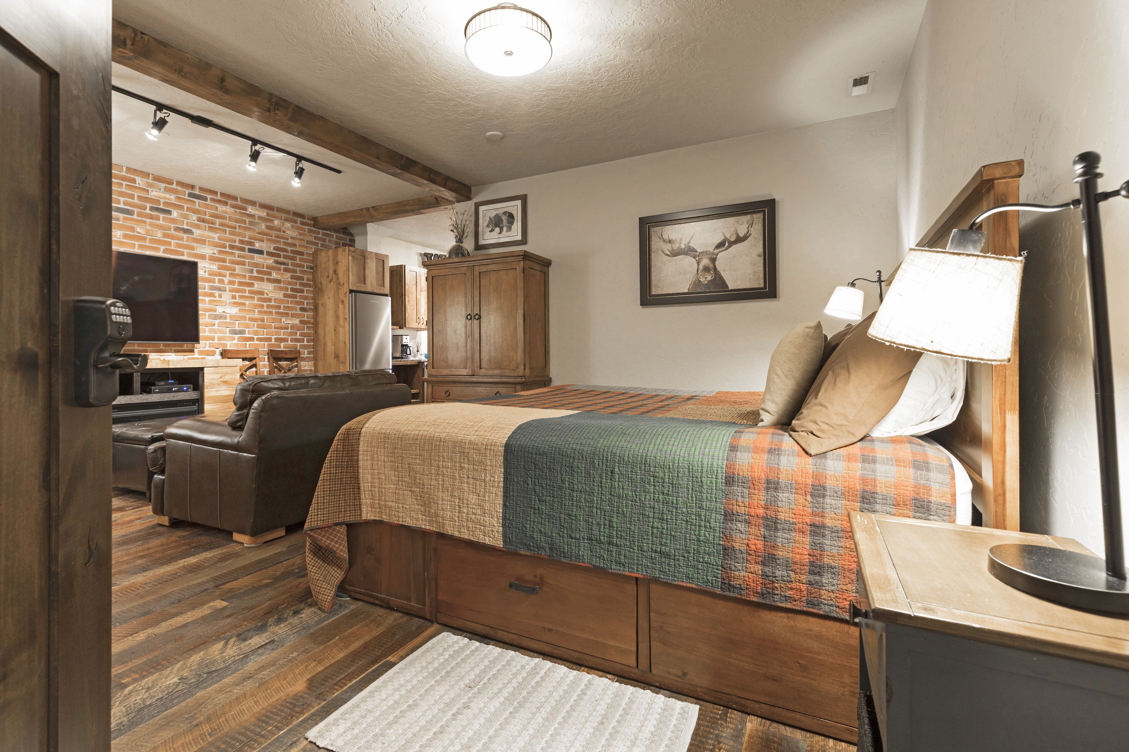 A bedroom with a bed, a desk, a chair, a lamp, and a television.