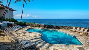 Zona de piscina con dos piscinas, sillones de descanso y vista al océano.