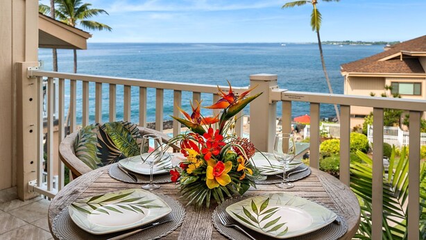 Mesa para dos con un centro de mesa de flor tropical, con vistas a la costa.