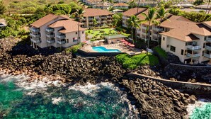 Un resort con varias edificaciones, piscina y un litoral rocoso.