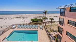 Ein Poolbereich mit Liegestühlen und Blick auf den Strand.