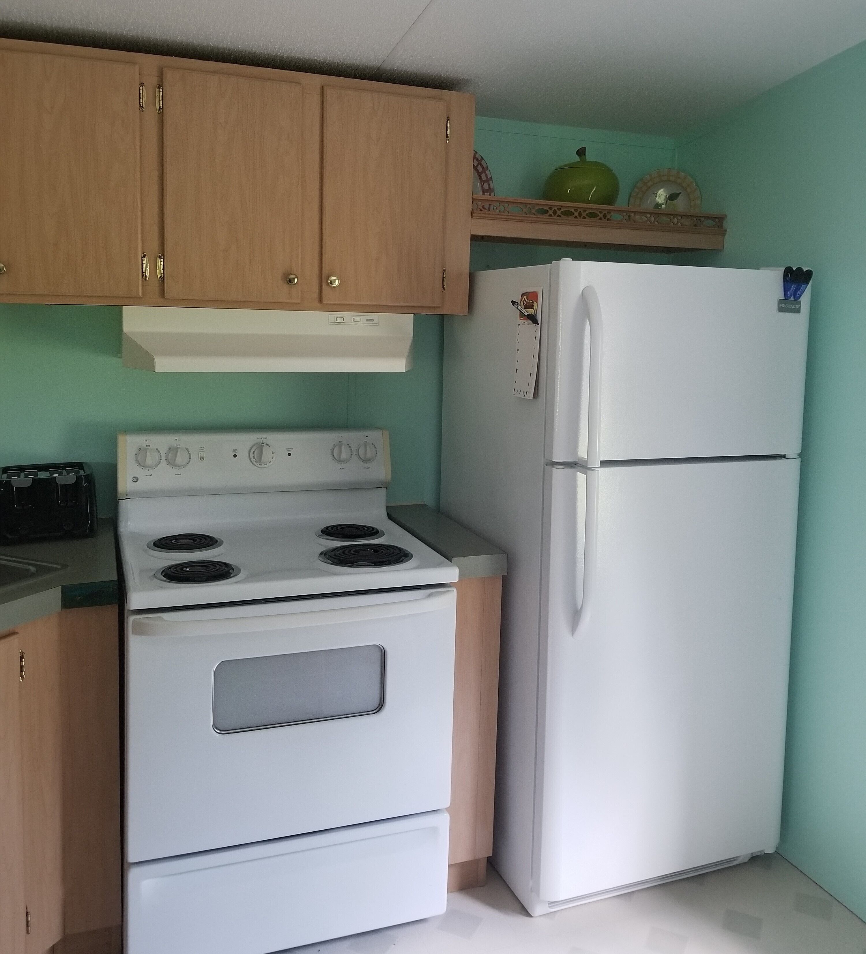 A kitchen with wooden cabinets, a white stove, and a white refrigerator.