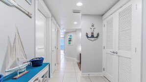 A hallway with white doors, a blue table with a sailboat model, and a wall-mounted anchor.