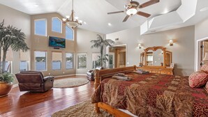 A spacious bedroom with a large bed, a ceiling fan, multiple windows, and a view of the outdoors. - Giant Lakefront Home with spectacular views of main channel - Lake of the Ozarks (Osage Beach)