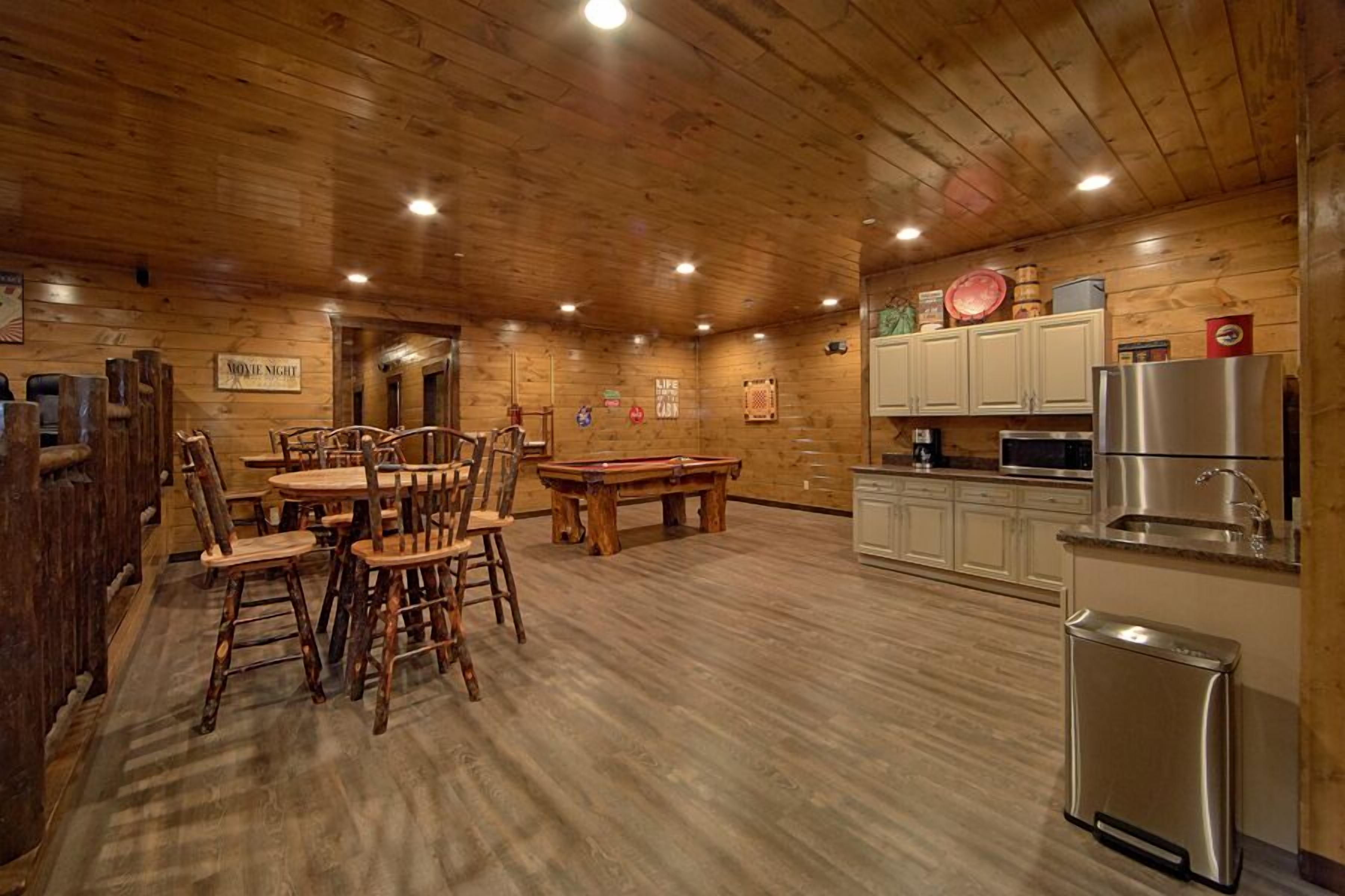 Un interior de madera con comedor, mesa de billar y cocina.