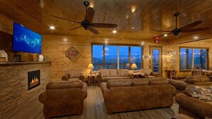 A cozy, wood-paneled room with leather sofas, a fireplace, and a television.