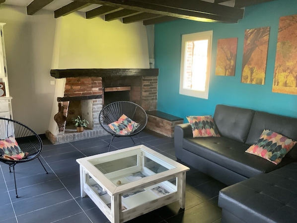 Uma sala de estar com lareira, um sofá, duas poltronas e uma mesa de centro.