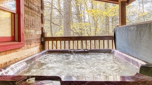 Ein Whirlpool mit Holzterrasse und Blick ins Grüne.