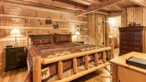 Ein Schlafzimmer in einer Blockhütte mit einem hölzernen Bett, einer Kommode und einem Nachttisch.
