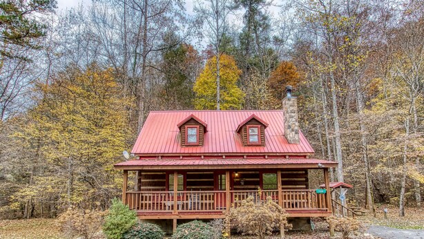 Eine Hütte mit rotem Dach, Holzfassade und einer Veranda.