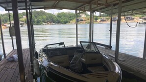 A boat docked at a wooden pier with a covered area overhead. - 3+ acres of woods and lake (Bremen)