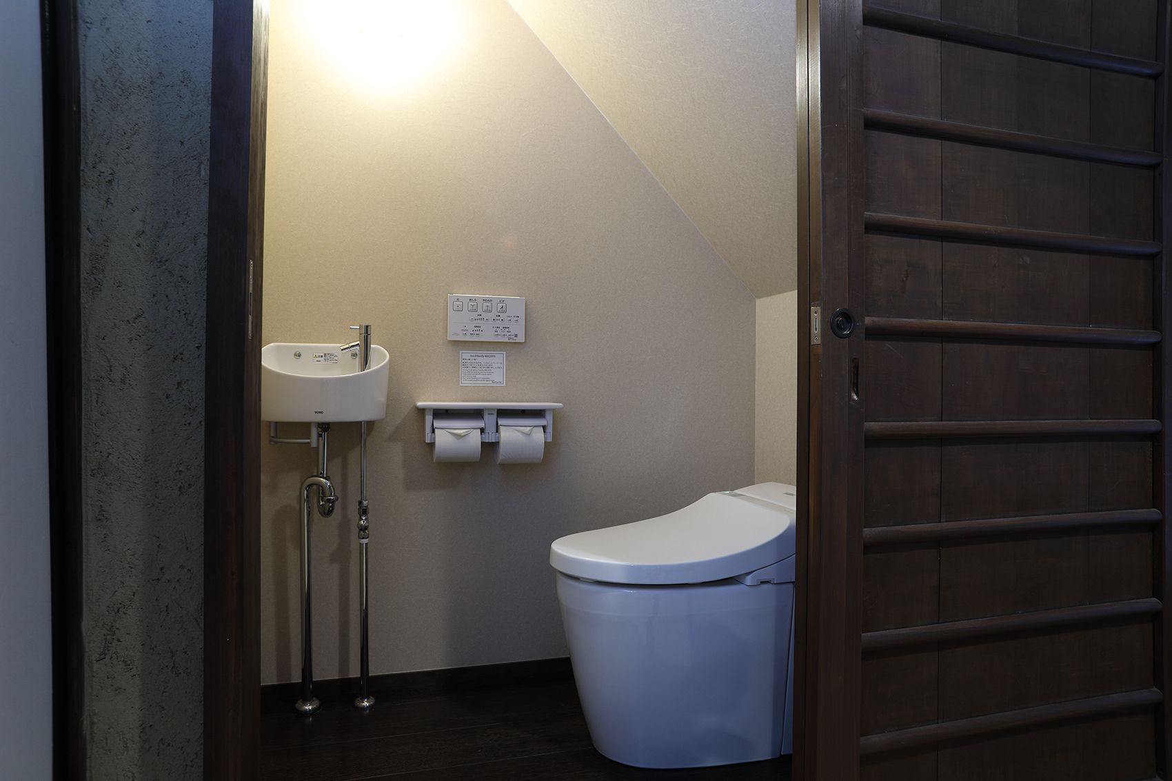 Un baño pequeño con inodoro, lavamanos y dispensador de toallas de papel.