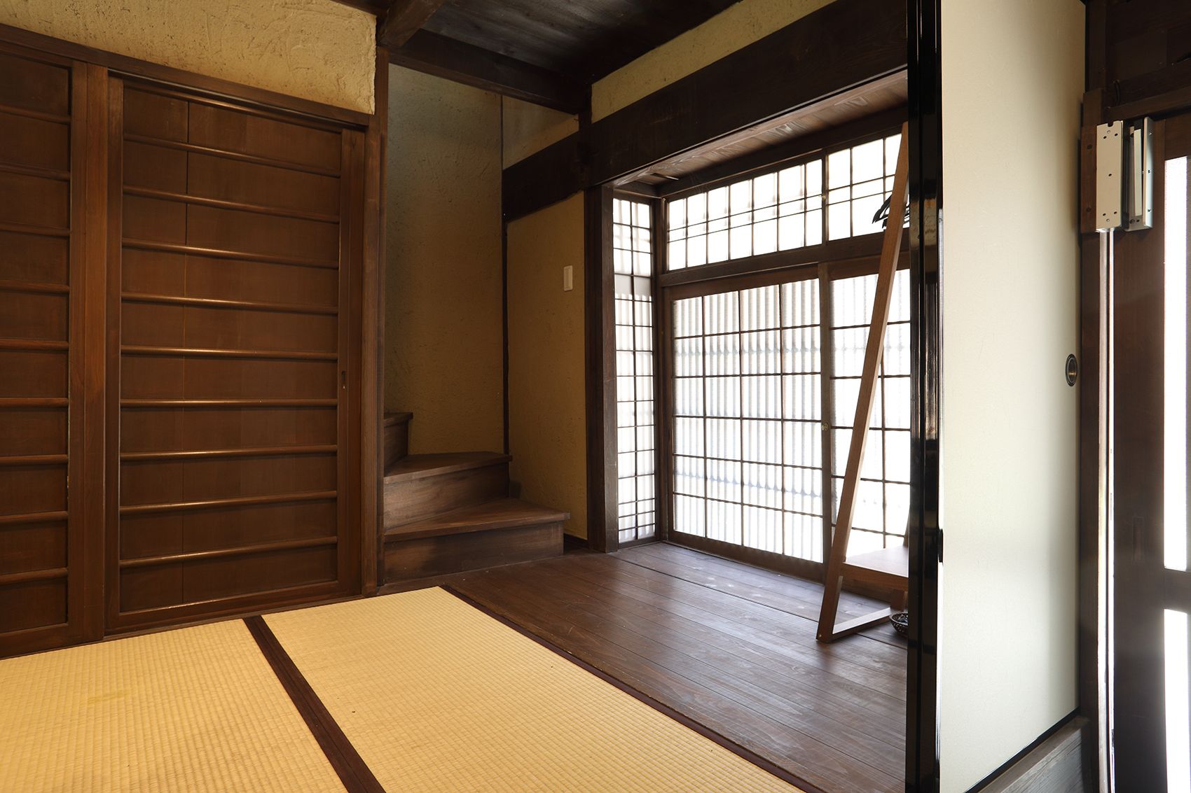 Een traditionele Japanse kamer met tatami vloerbedekking, een schuifdeur en uitzicht door een shoji scherm.