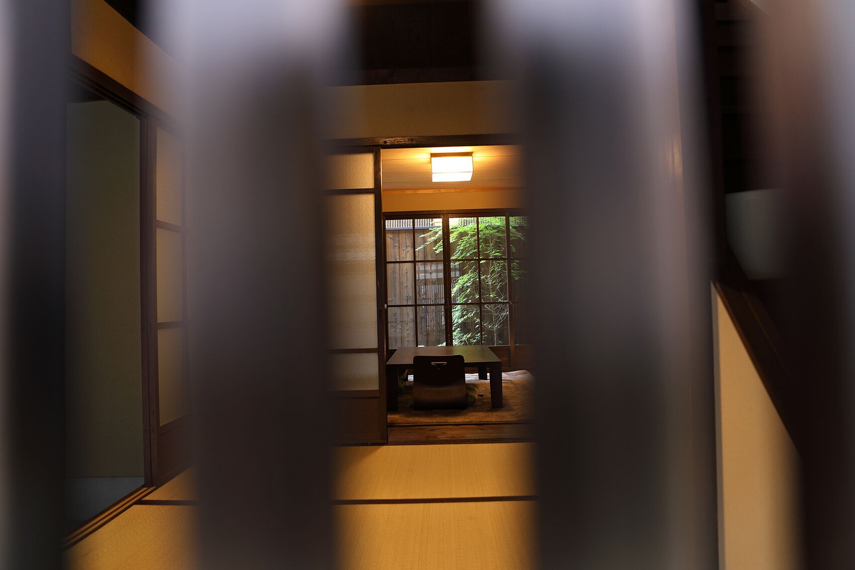 Un pasillo con un banco de madera y una pequeña mesa, que conduce a una habitación con ventana.