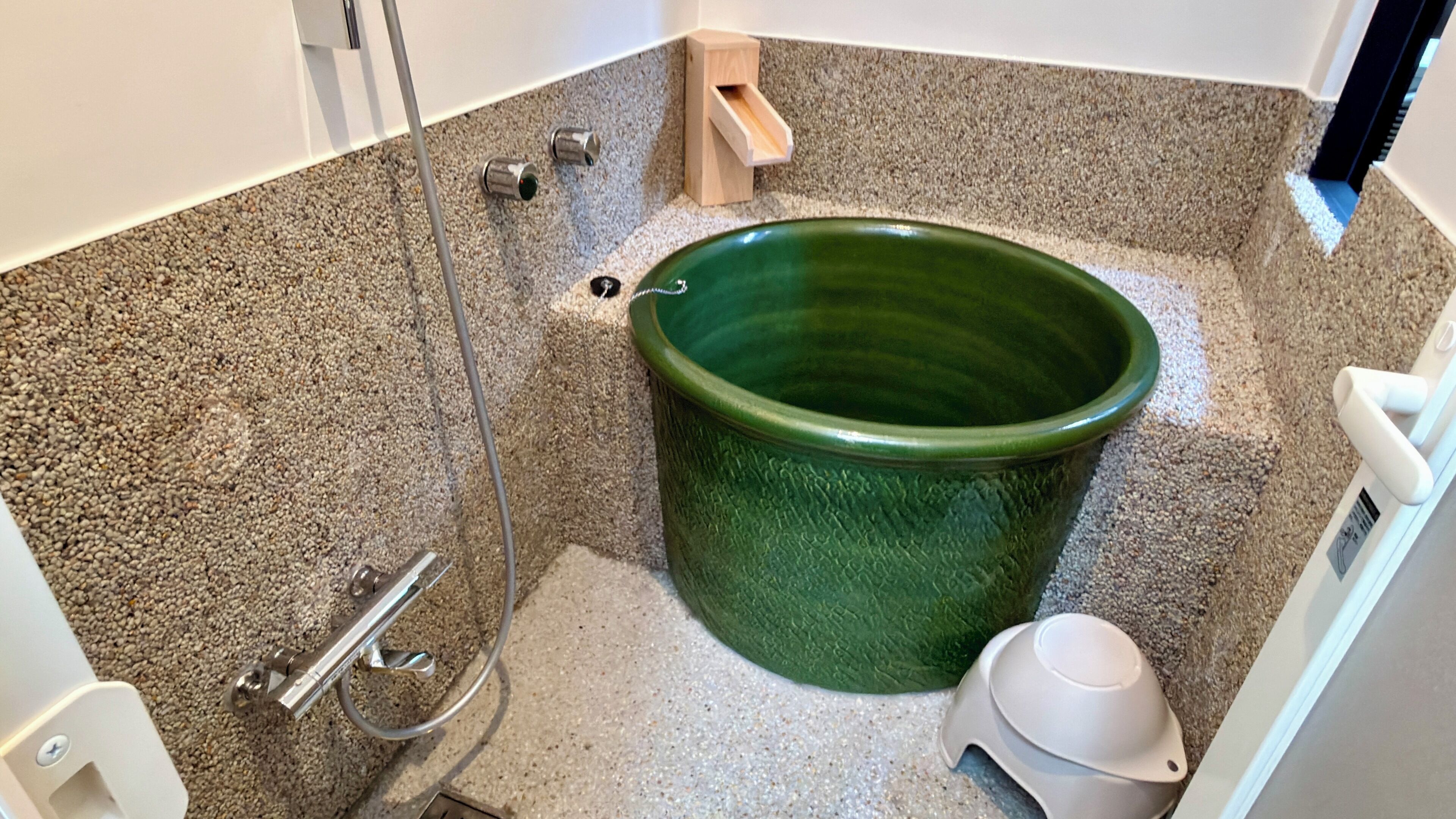 A bathroom with a green ceramic tub, a shower, and a toilet.