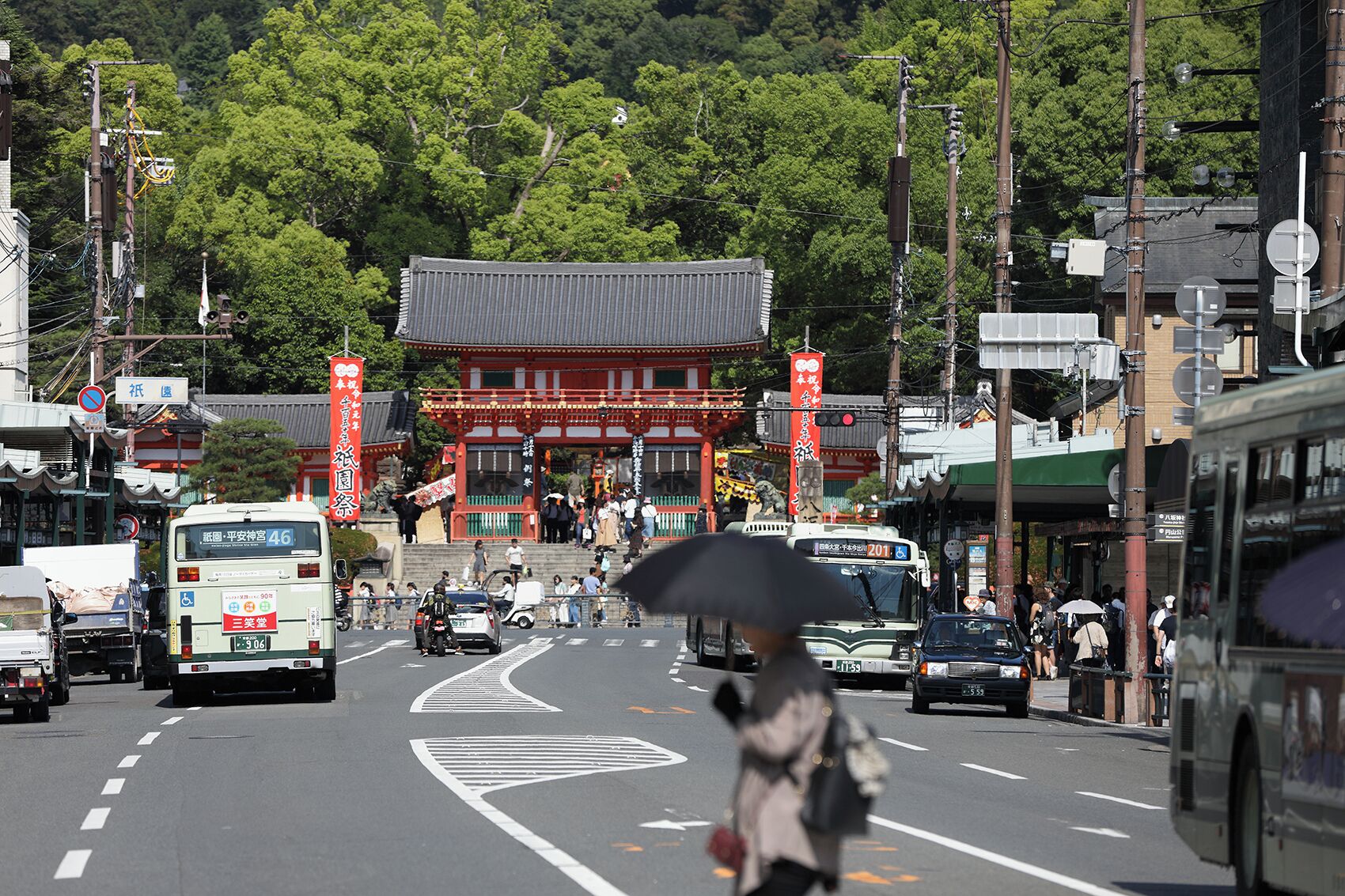 A street with a traditional building, vehicles, and pedestrians.