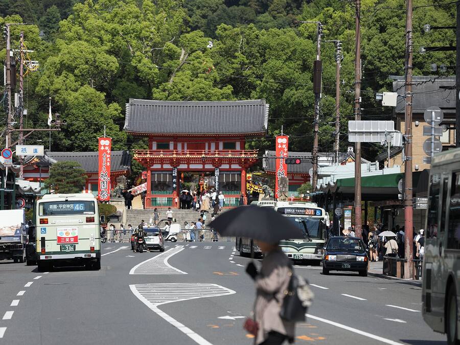 A street with a traditional building, vehicles, and pedestrians.