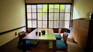 Un comedor con una mesa, sillas, un ventanal con vista a una valla de madera y un armario.