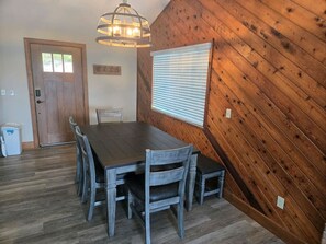 A dining area with a wooden table and chairs, a window with blinds, and a door with a small window. - Serenity In The Smokies, Great View, great locatio (Sevierville)