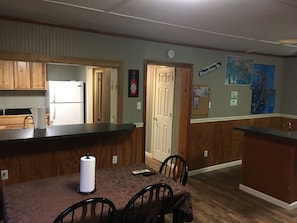 Kitchen area with a central island, refrigerator, sink, and wooden flooring.