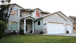 Une maison à deux étages avec un garage, un porche à l’avant et une pelouse bien entretenue.