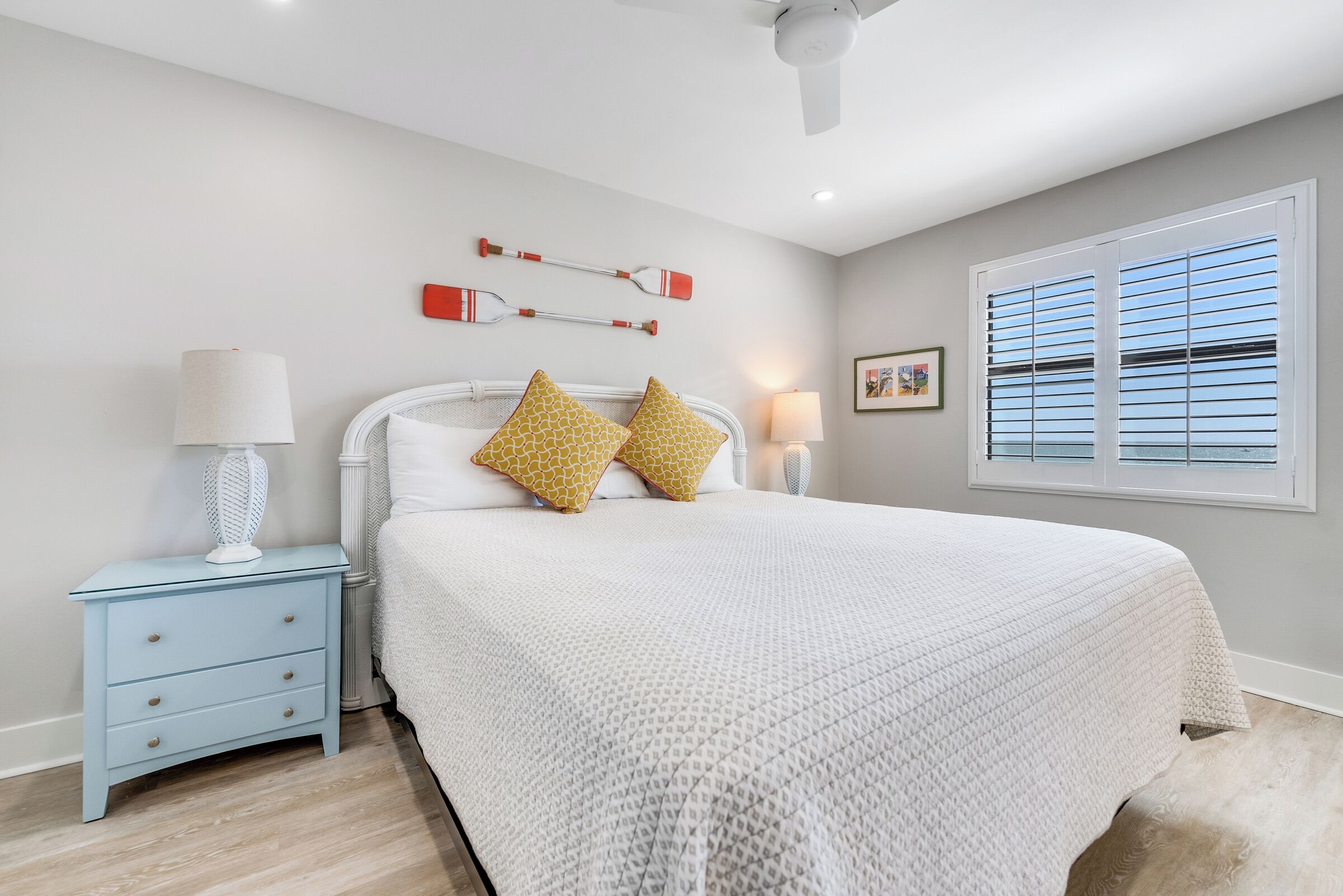 A bedroom with a bed, nightstands, a ceiling fan, and a window with blinds.