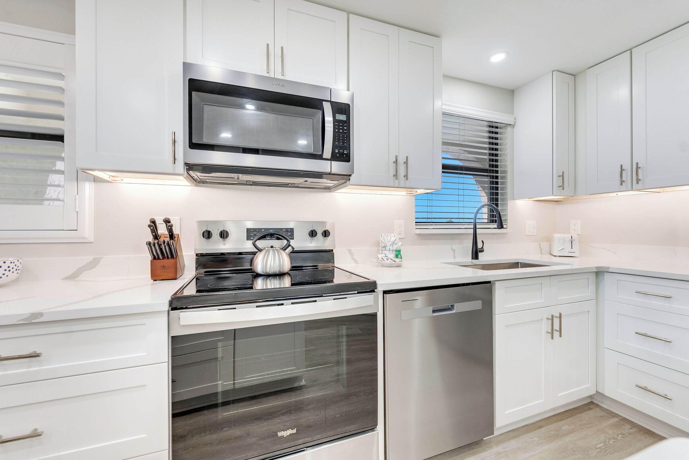 A modern kitchen with white cabinets, stainless steel appliances, and a built-in oven.