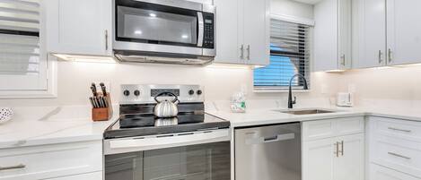 A modern kitchen with white cabinets, stainless steel appliances, and a built-in oven.