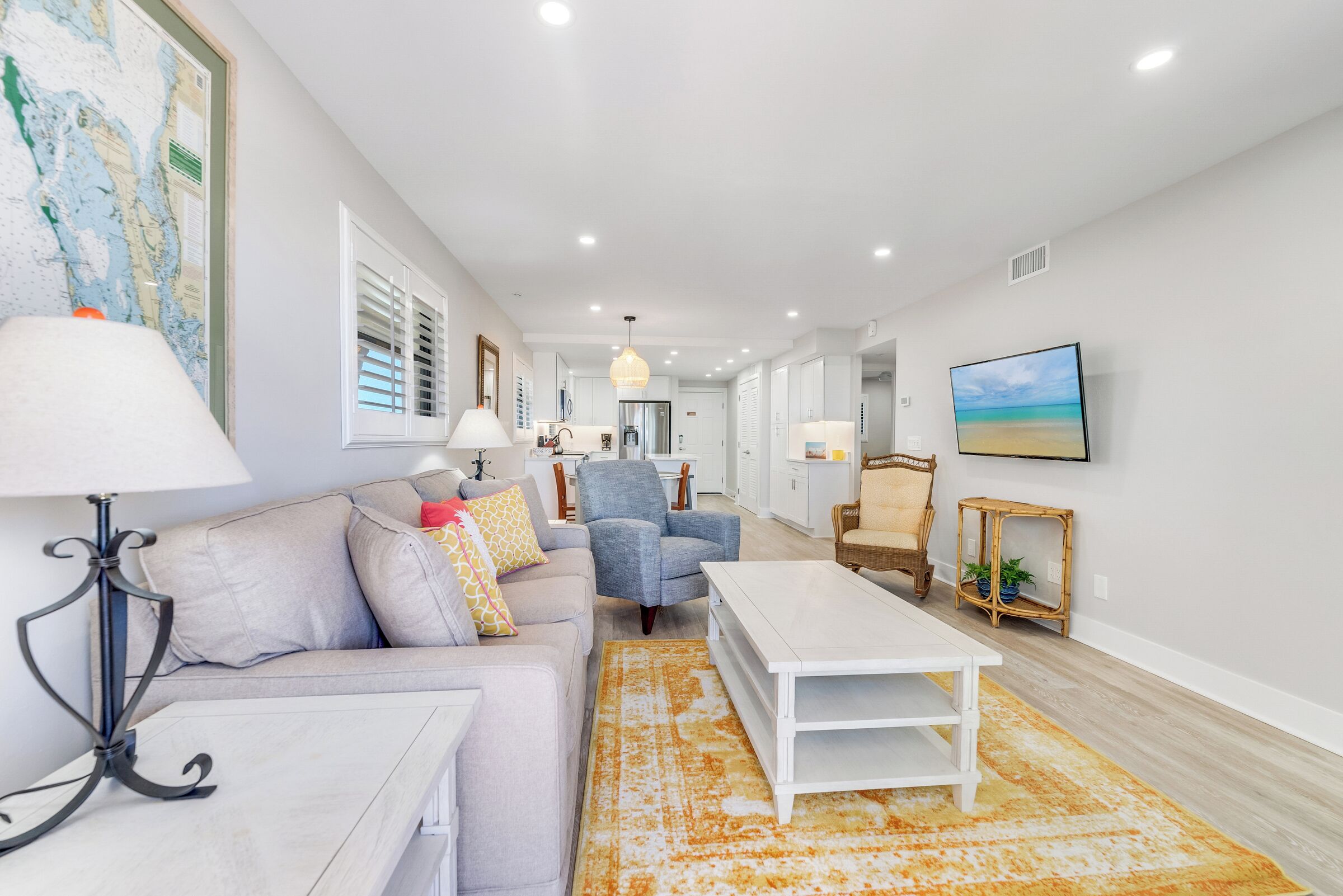 A spacious living room with a sofa, armchair, coffee table, and a large rug.