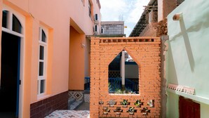 A narrow alleyway with a brick archway, a tiled floor, and a small window with plants. - New Dap Hostel in Grape Town (Turpan)