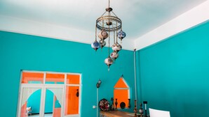 A room with turquoise walls, a wooden bar area, and a hanging chandelier. - New Dap Hostel in Grape Town (Turpan)