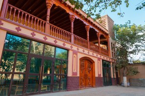 A building with a balcony, large windows, and a wooden door. - New Dap Hostel in Grape Town (Turpan)