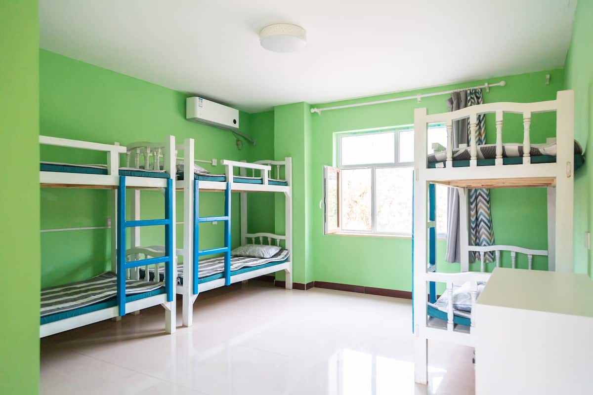 Quarto com beliches, janela e luminária branca no teto.