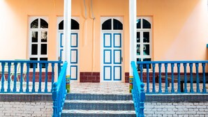A building with two blue doors, a tiled entrance, and a brick wall. - New Dap Hostel in Grape Town (Turpan)