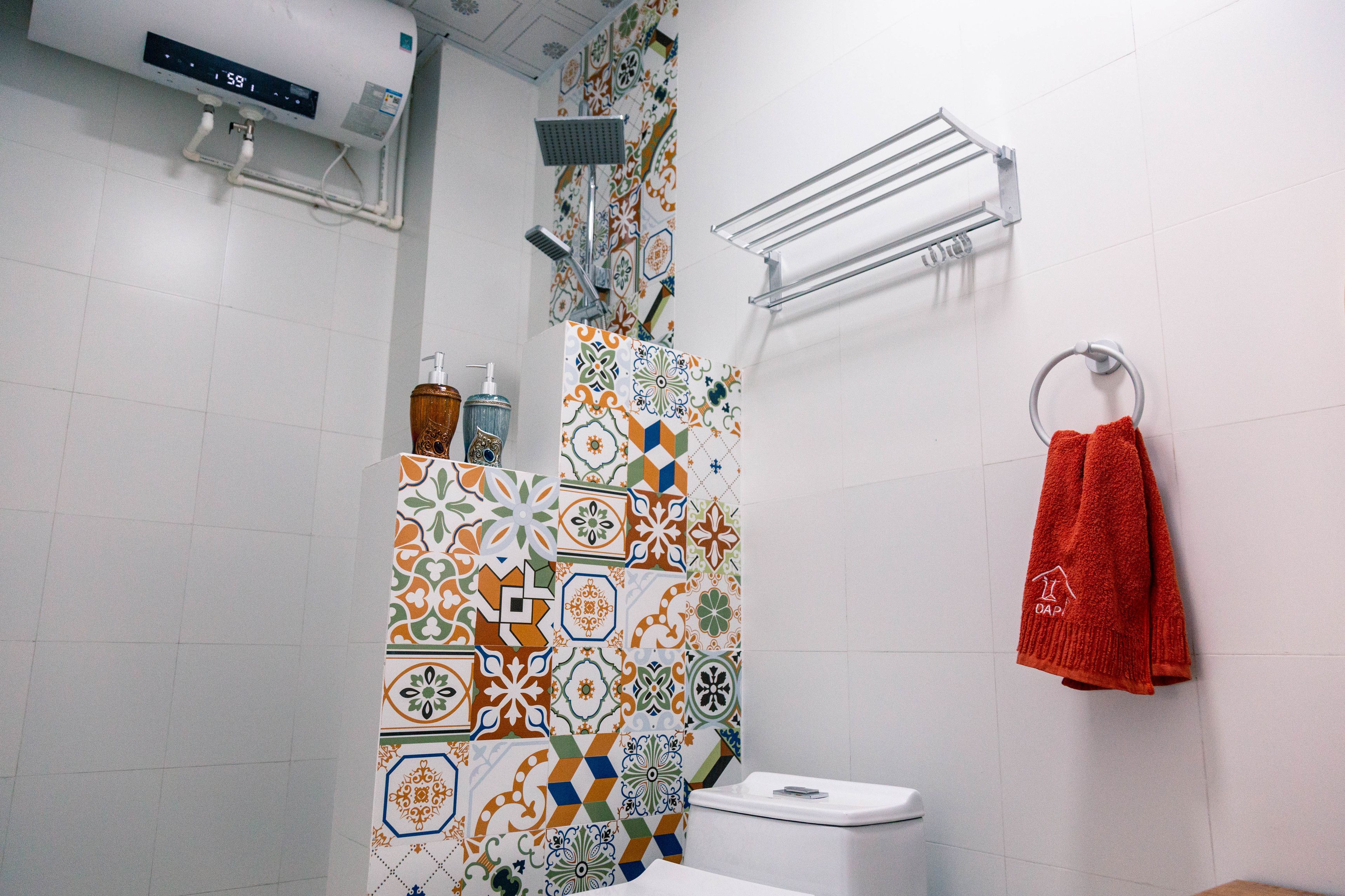A bathroom with a shower, toilet, and a towel rack with a red towel.