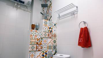 A bathroom with a shower, toilet, and a towel rack with a red towel.