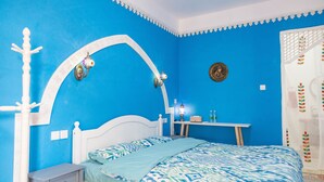 A bedroom with a bed, a nightstand, a desk, and a wall-mounted lamp. - New Dap Hostel in Grape Town (Turpan)