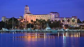 A large hotel with a prominent tower, waterfront marina, and palm trees. - What a View! Low Rates! 5-STAR! Waterfront, 2BR, private balcony, walk to Beach! (Treasure Island)